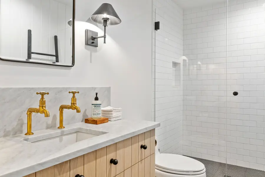 Bath with brass faucets, marble top and subway tile
