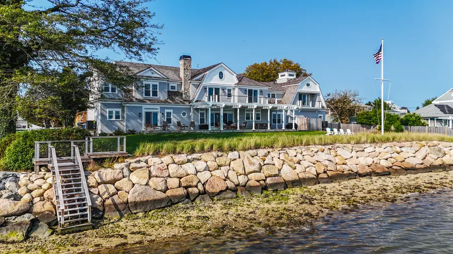 Shingled waterfront home on Hyannis Harbor behind a stone seawall