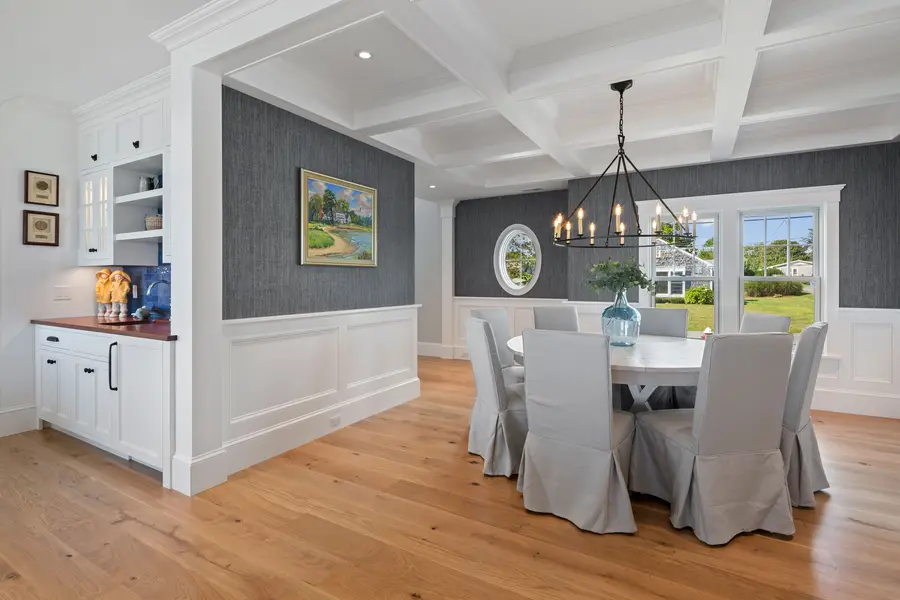 Dining room under a coffered ceiling, with the wet bar built-ins on the left