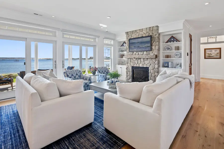 Living room with a stone fireplace, built-ins and a wall of harbor-view windows