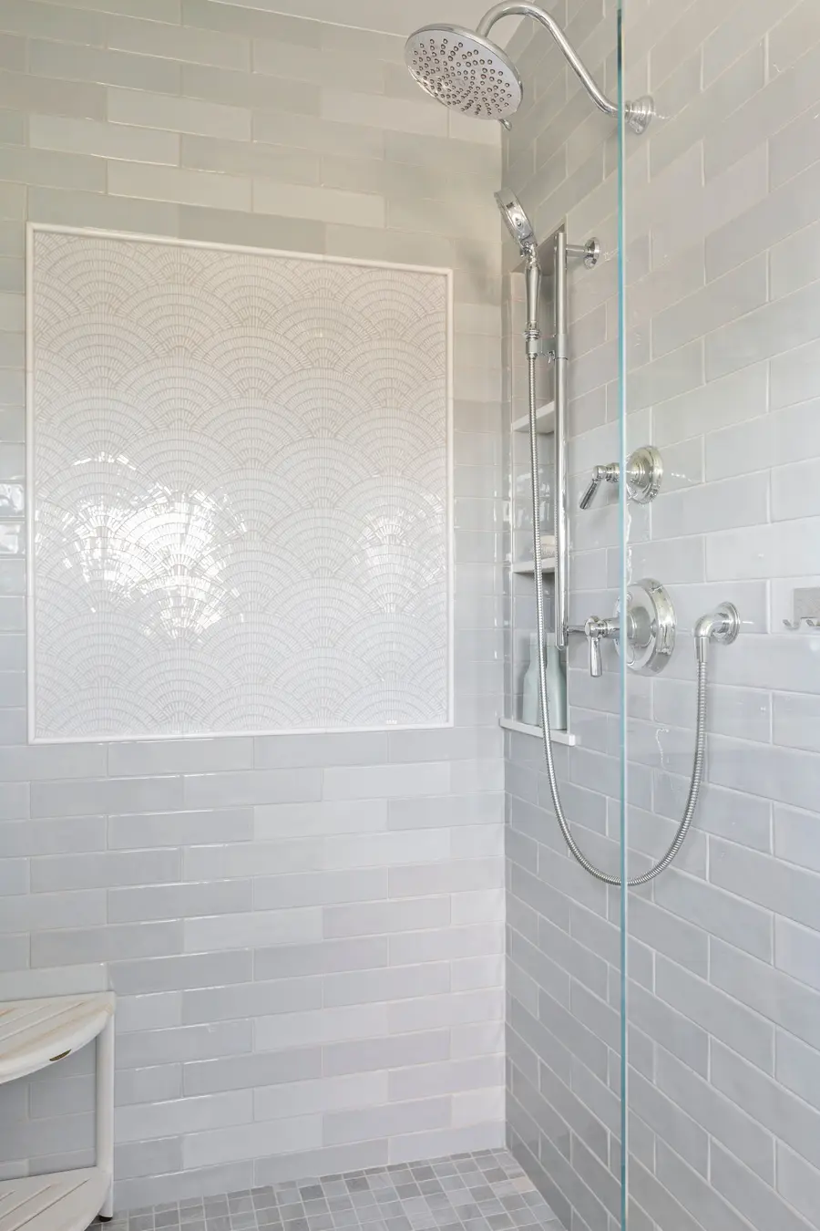 Walk-in shower in white tile with a glass door
