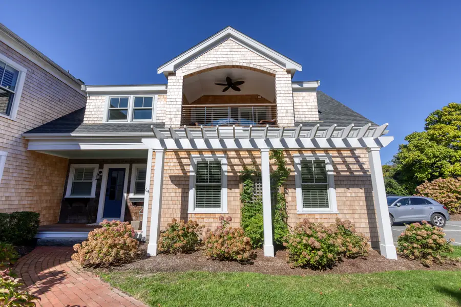 Shingled beach house with a white pergola over the front entry