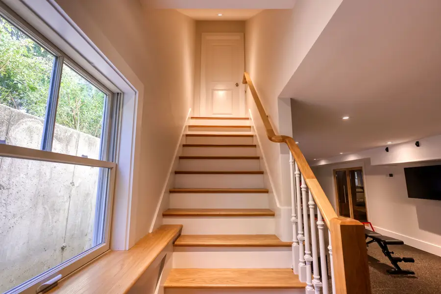 Stairway with a wood handrail and a window well