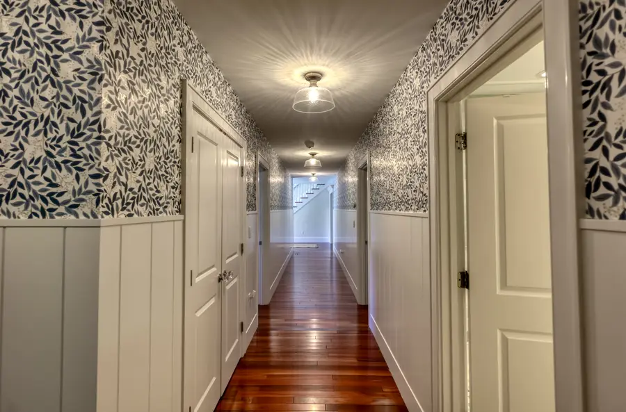 Upstairs hallway with leaf wallpaper and wainscoting