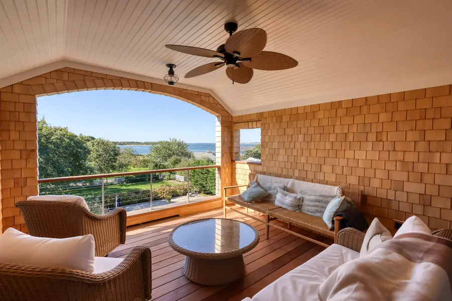 Cedar-shingled covered porch opening to the water