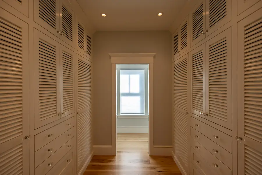 Hallway lined with built-in louvered closets and drawers