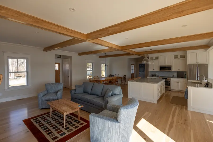 Open great room with beamed ceiling, living area and kitchen beyond