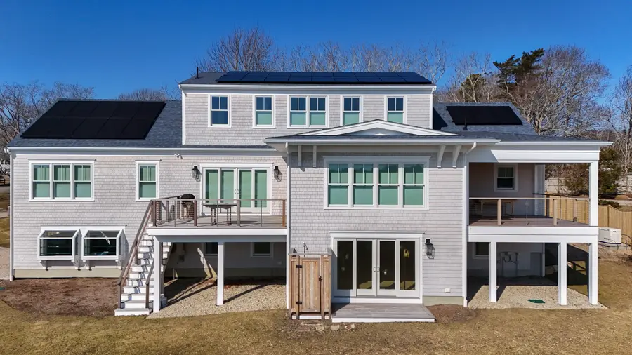 Water side of the house with stacked decks and a covered porch