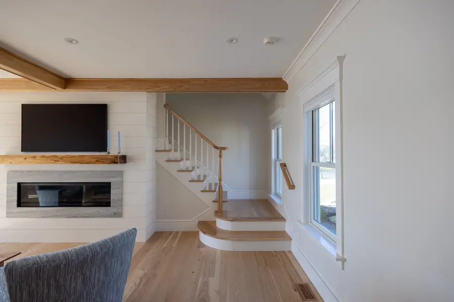 Shiplap wall with the fireplace and an open stair with a white-oak rail